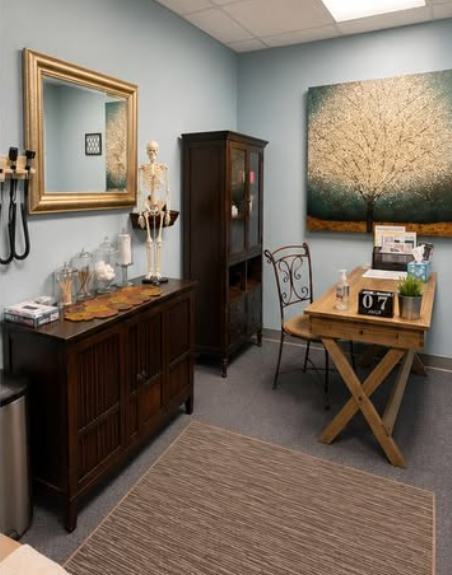 A treatment room with an exam table and framed artwork